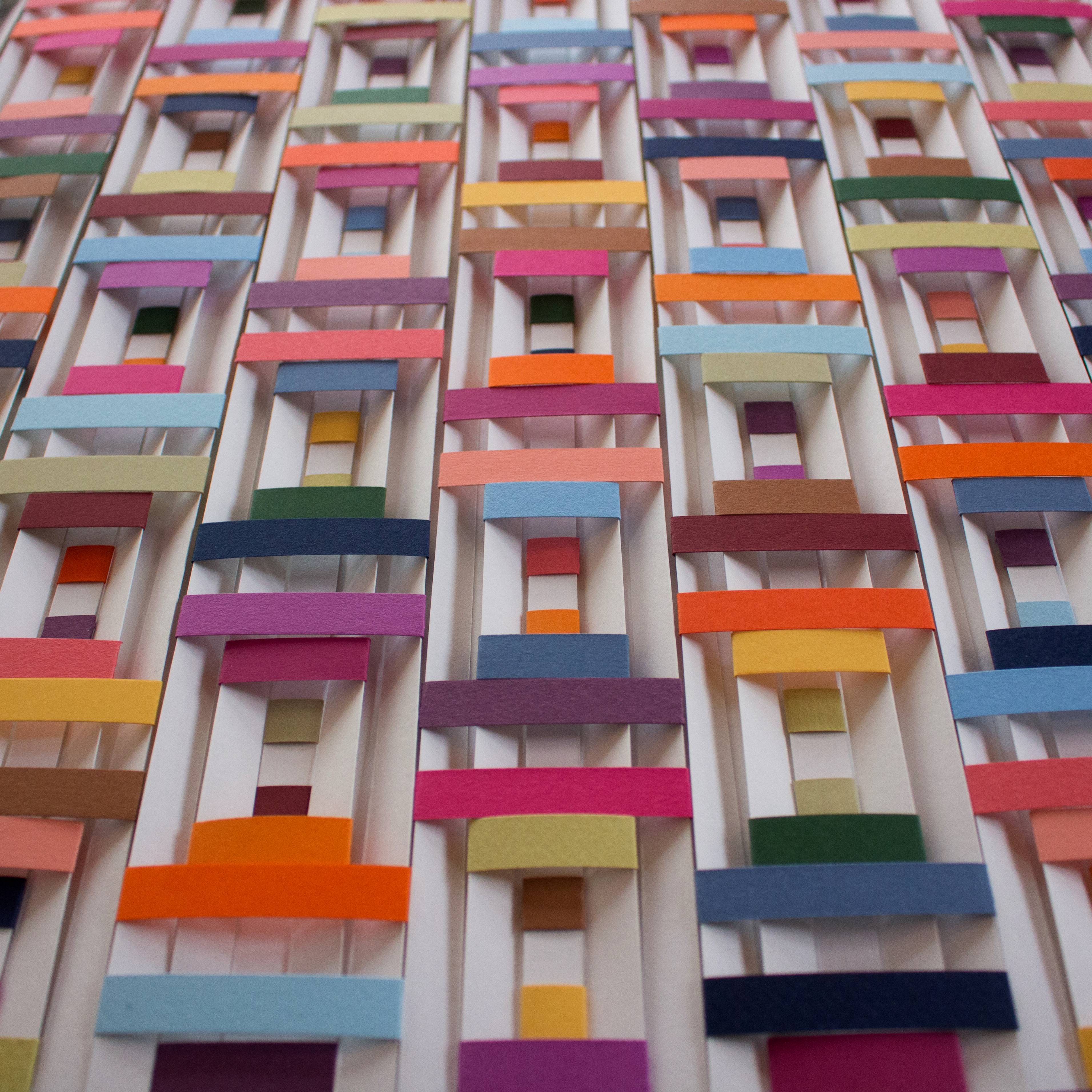 paper artwork featuring multicolored strips of paper across vertical white strips of paper